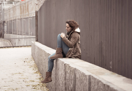 有吸引力的女人患有抑郁症，感到悲伤不快乐心碎和孤独，坐在城市街道上，心理健康情感痛苦虐待关系和孤独观念。