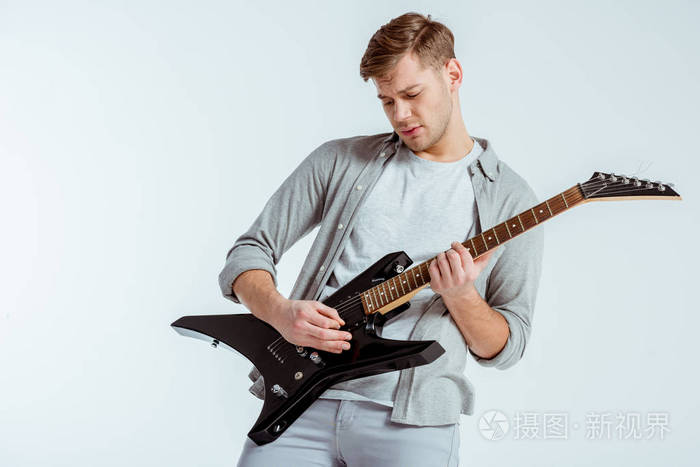 一个穿灰色衣服的英俊专注的男人在灰色中弹电吉他