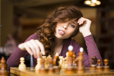 美丽的女人下棋, 看着镜头。该你了