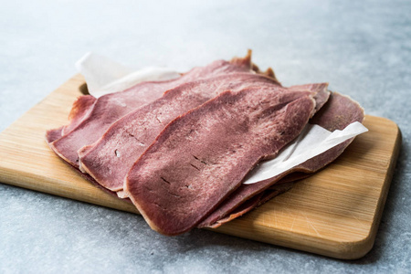 切片牛肉舌片在木板上。 有机熏肉。