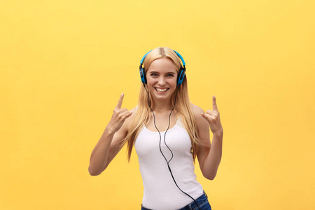 生活方式概念 一个快乐的女人在白色 t恤和听音乐用耳机, 同时跳舞和唱歌孤立在黄色背景的肖像