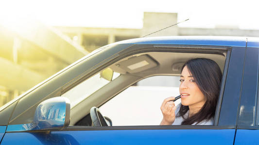 快乐的女人在开车的时候涂口红概念表达和手势
