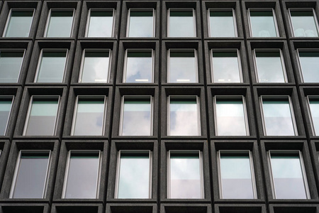 现代城市商业大厦摩天大楼的底部玻璃灰色方形窗户。后退的视角，向前和向上移动。底层查看办公楼窗户收口..