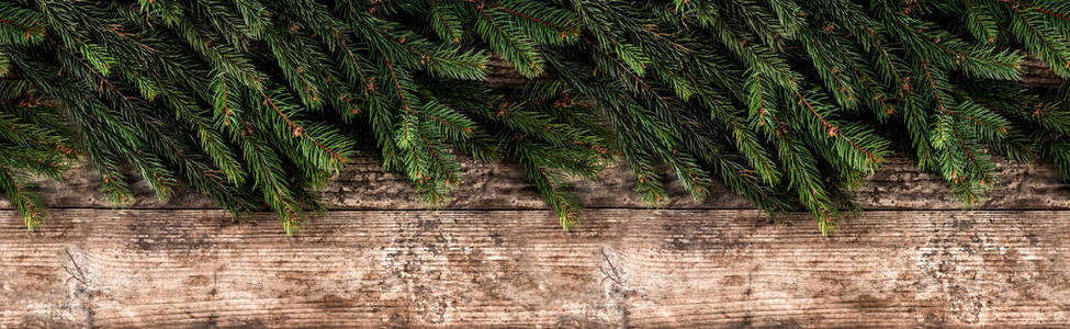 创意布局框架由圣诞杉木树枝在木制背景。 圣诞节和新年主题。 平躺式顶部宽幅构图