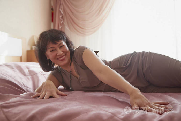 床房里漂亮的中年女人.家里的女士一天休息一下.室内用紫丁香色调拍摄