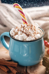 一杯热巧克力，上面有棉花糖和一根棒棒糖棒在针织毛毯背景上。 一个舒适的圣诞家庭假日的概念