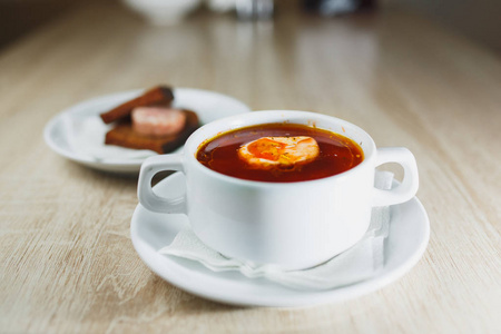 乌克兰传统博尔施。 俄罗斯素食红汤在白色碗上的红色木制背景。 上面的风景。