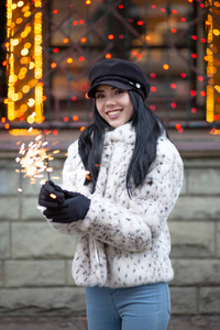 戴着黑色帽子在花环上庆祝新年的时髦微笑的黑发女人模糊的背景