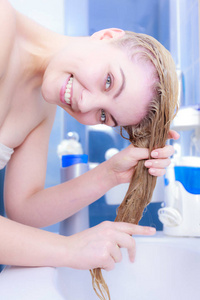 快乐的女人有湿的金发。 积极的女性将要洗她的发型