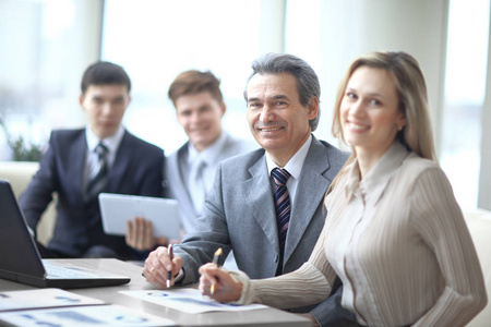 成熟的业务人在会议上与背景的同事中微笑的肖像