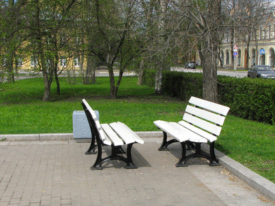 公园里两张白色的长凳相对而立。 供朋友使用的长椅