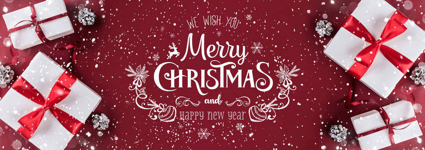 圣诞礼品盒与红色丝带装饰松果在白色和红色纸背景。 圣诞节和新年快乐主题。 平躺式顶部视图