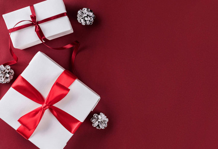 圣诞礼品盒与红色丝带装饰松果在白色和红色纸背景。 圣诞节和新年快乐主题。 平躺式顶部视图