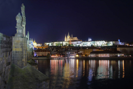 在布拉格夜拍摄的照片。 在明亮的堡垒的照片中，名叫维塞赫拉德。 灯光反射在Vltava河上。 前景是查尔斯桥的雕像。