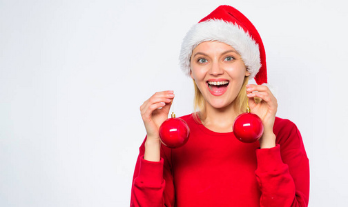 女人戴圣诞老人帽子举行两个球装饰饰品的圣诞节。轻松的冬季装饰。添加节日的气氛你的假期。新年装饰的概念。冬天是如何装饰的。圣诞树装
