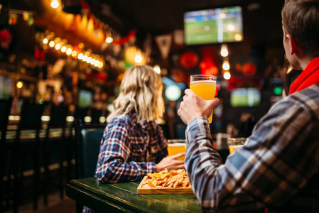 快乐的朋友在体育酒吧里看比赛和喝啤酒