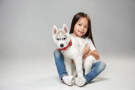 一个快乐的小女孩的肖像与西伯利亚哈士奇小狗在地板上的工作室