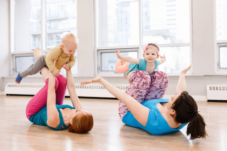 两组年轻妇女带着孩子在体育课上锻炼，以减轻婴儿体重。 儿童友好健身为有孩子的母亲。 母亲家庭活动的生活方式概念。