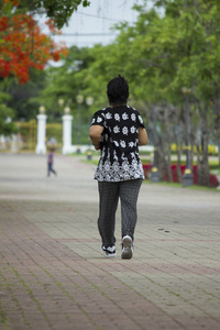 一位穿着黑色衣服的老妇人在公园里跑步。