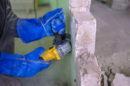 建筑工人用电动切割机切割混凝土墙。 危险的工作。 建筑工程