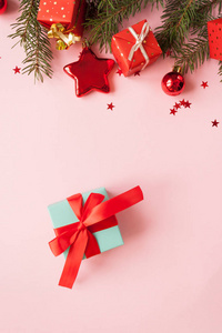 圣诞快乐，新年快乐。 圣诞卡节日与绿色冷杉枝和礼物与红色蝴蝶结在粉红色背景。