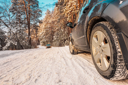 豪华的黑色交叉在森林的冬季道路上停了下来。 suv. 冬天道路上的汽车轮胎覆盖着雪。 早上下雪时，雪巷上的车辆。