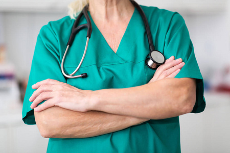 s torso in scrubs and a stethoscope and her arms folded