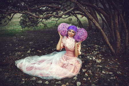 穿着粉色连衣裙的漂亮模特正在用创意假发摆姿势