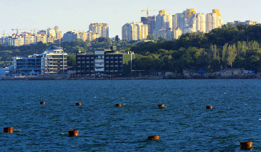 壮丽的全景从海洋到沿海地带的城市日落前在柔和的阳光。 岸上的高层建筑和商业设施