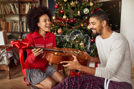 快乐的女人给男人一个惊喜，带着吉他礼物送给圣诞节
