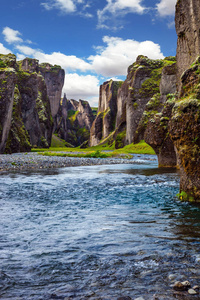 峡谷冰岛童话和传说FyadrarGlyufur。 陡峭的悬崖上长满了绿色的苔藓，四周环绕着一条非常快的河水和冷水