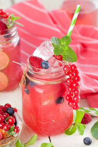 夏日浆果饮料。 柠檬水与覆盆子和黑莓与柠檬薄荷在梅森罐子在白色桌子上。