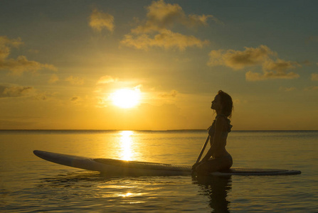 日落时冲浪板上的快乐女人