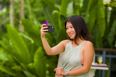 年轻快乐迷人的亚洲韩国女性，在热带岛屿上用手机自拍，摆出愉快轻松的姿态，探索丛林和自然，享受假期旅行