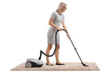 一个女人用吸尘器清洁地毯的完整镜头，隔离在白色背景上