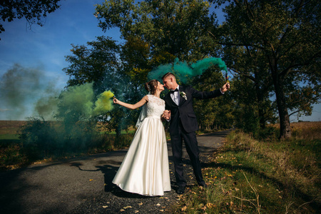 婚礼夫妇手里拿着颜色的烟雾在巷子的中央