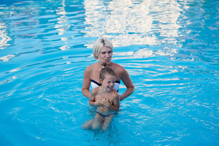 幸福的母亲和女儿在游泳池里玩