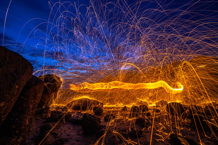 冷火太阳升起时在岩石上进行冷燃烧钢、羊毛、火的工作照片实验照片