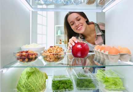 女性站附近打开冰箱充分的健康食品，蔬菜和水果的肖像