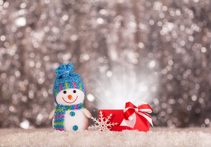 微笑的雪人和一个神奇的礼物在雪地上明亮的灰色背景
