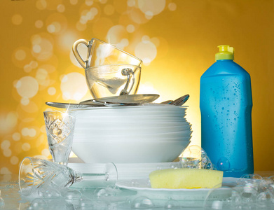 用肥皂泡在黄色背景上清洗碗碟和杯子洗洁精和海绵