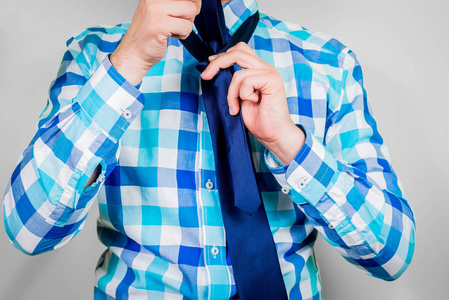 戴上领带。 那个人拿着领带。 系领带的说明。 温莎节点的准备。 穿蓝色衬衫的男人的正面景色。