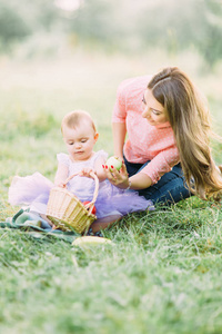 快乐的母子宝贝女孩在盛开的春天花园里玩水果。母亲节假期概念