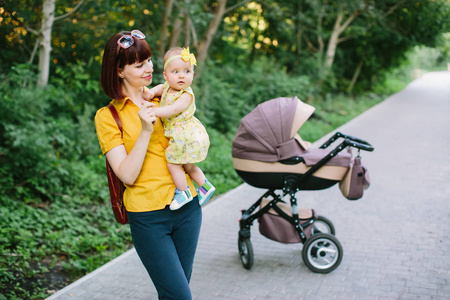 家庭孩子和父母的概念快乐的母亲从后面和婴儿车在公园散步