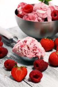 草莓和覆盆子冰淇淋舀碎坚果和白巧克力在乡村背景