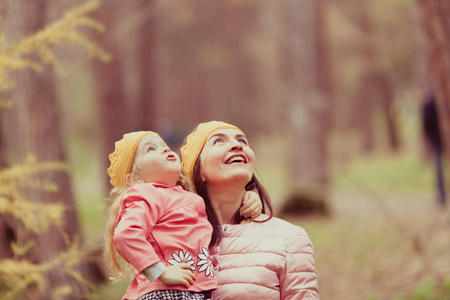 美丽的女孩和母亲穿着针织皇冠走在秋天公园户外