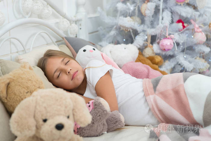 小女孩躺在床上拿着玩具.可爱的女孩在圣诞之夜睡着了.
