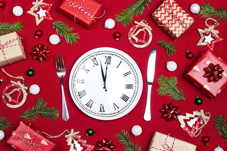 节日餐桌设置与盘钟和圣诞装饰在红布背景。 上面的风景。 圣诞餐具。