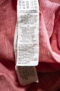 棉花和亚麻成分的标签。 粉红色衬衫上的特写标签。