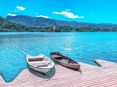 两艘木船停泊在蓝色湖泊上的木墩上，在斯洛文尼亚流血